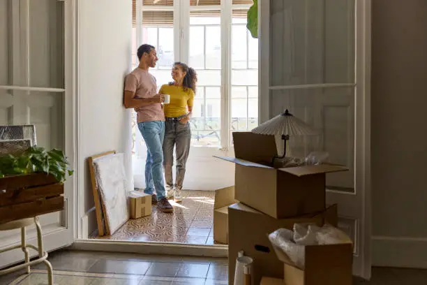 Couple standing in the doorway of their new home among moving boxes