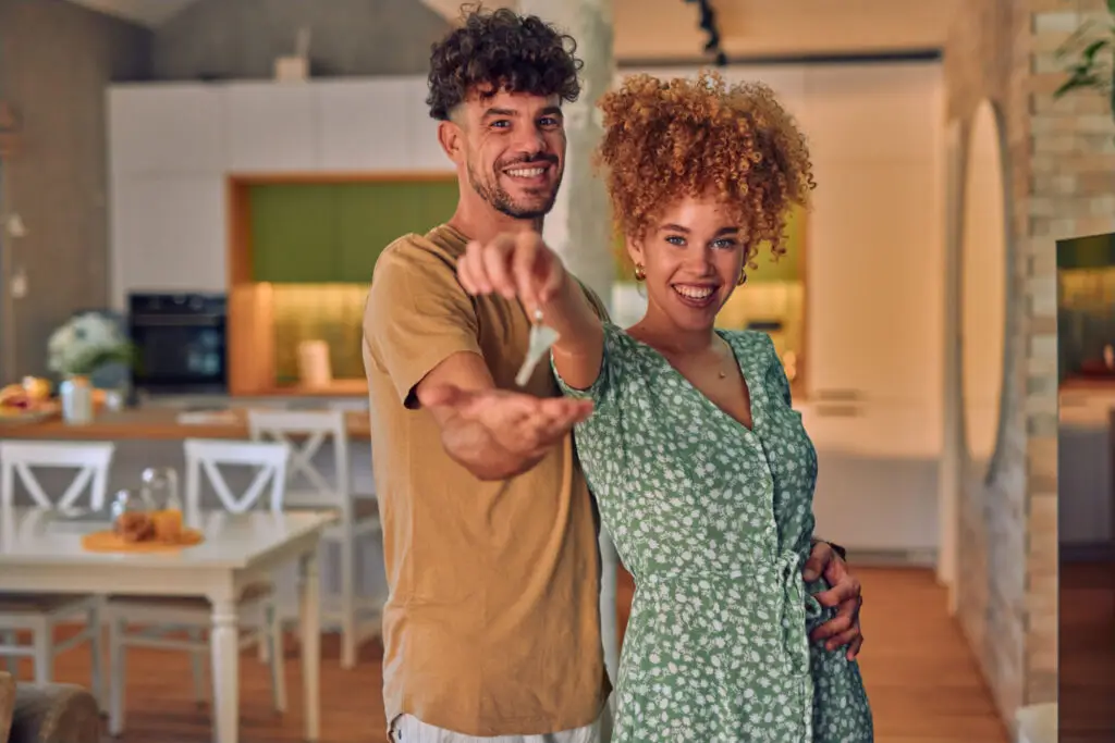 Happy couple holding the keys to the home they bought with an FHA loan