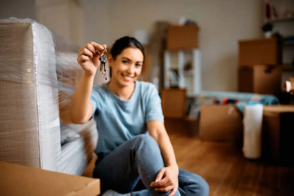First time homebuyer smiling and holding up the keys to her new home