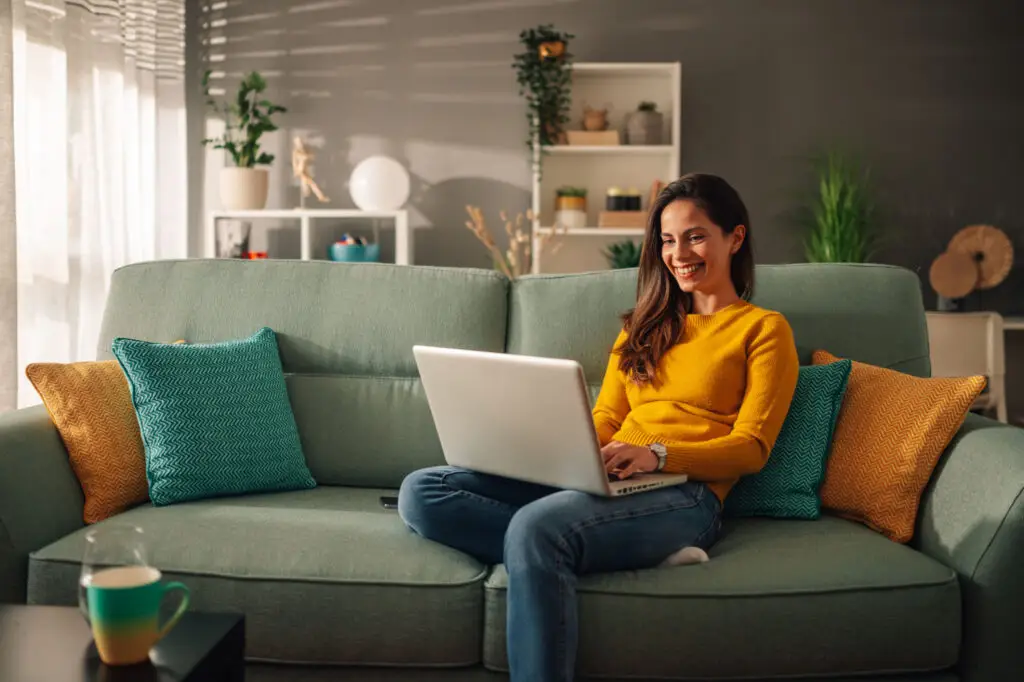 Woman working on a laptop while sitting on her living room sofa