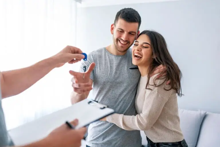 Couple laughing as an agent with a clipboard hands them house keys
