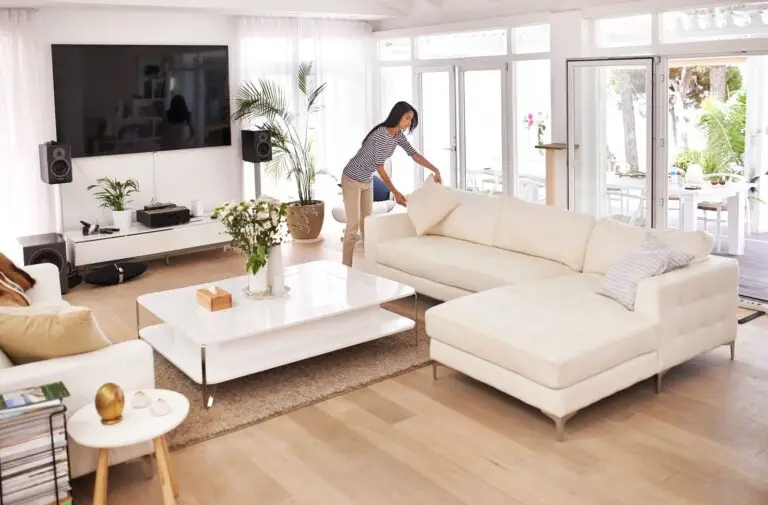 Woman arranging cushions on a white sectional sofa in a bright living room