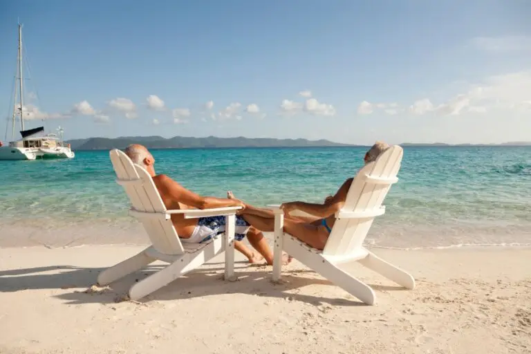 Couple relaxing in white wooden beach chairs on a tropical beach