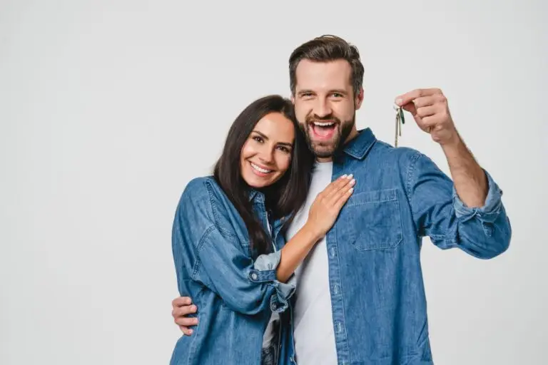 Happy couple in denim shirts holding up the keys to their new home