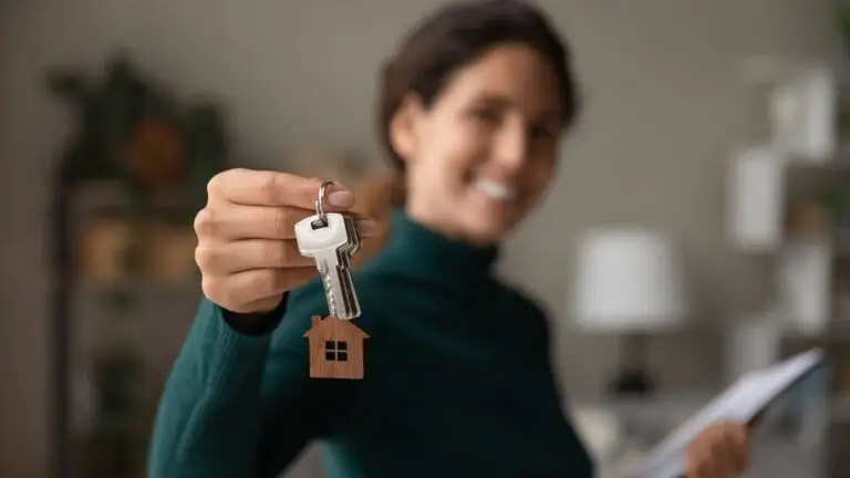 Agent holding out house keys on a small house keyring