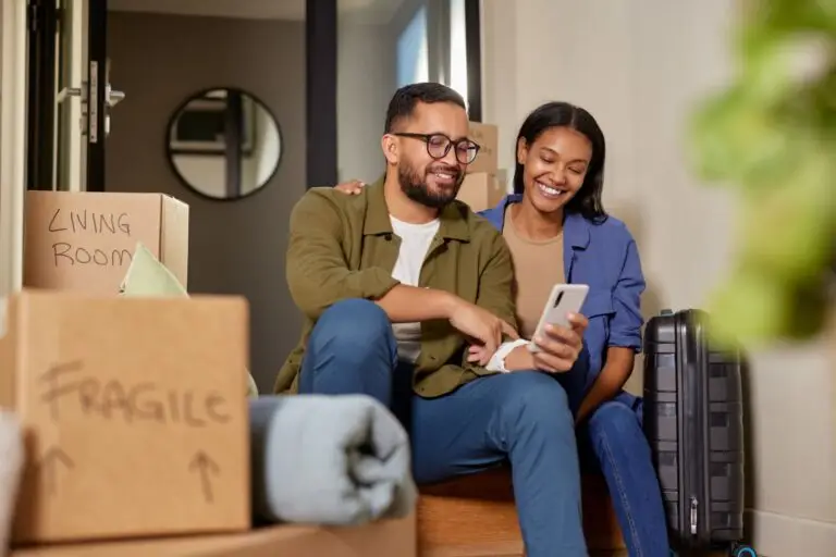 Couple sitting among moving boxes and looking at a phone