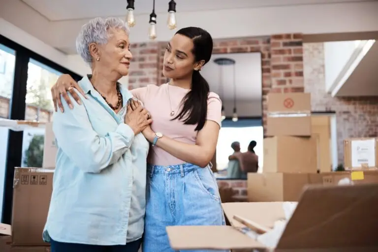 Older woman and a younger woman hugging among moving boxes at home