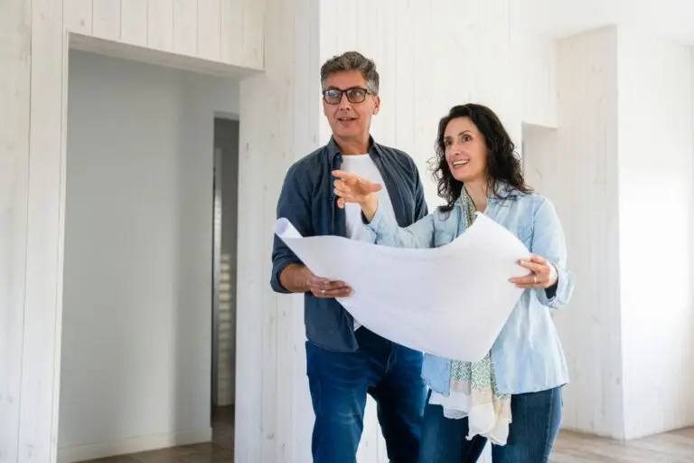 Couple reviewing building plans together inside a bright room under renovation