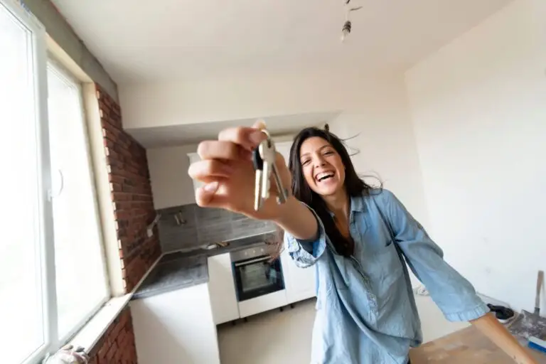Laughing woman in a denim shirt holding up a set of house keys