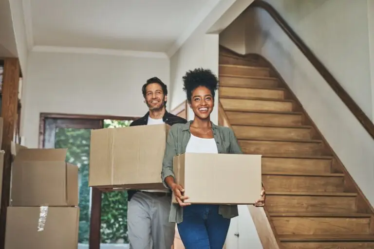 Couple carrying moving boxes into a home financed with an FHA loan