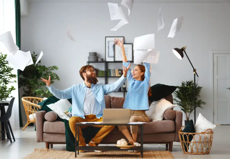 Excited couple tossing papers into the air in their bright living room