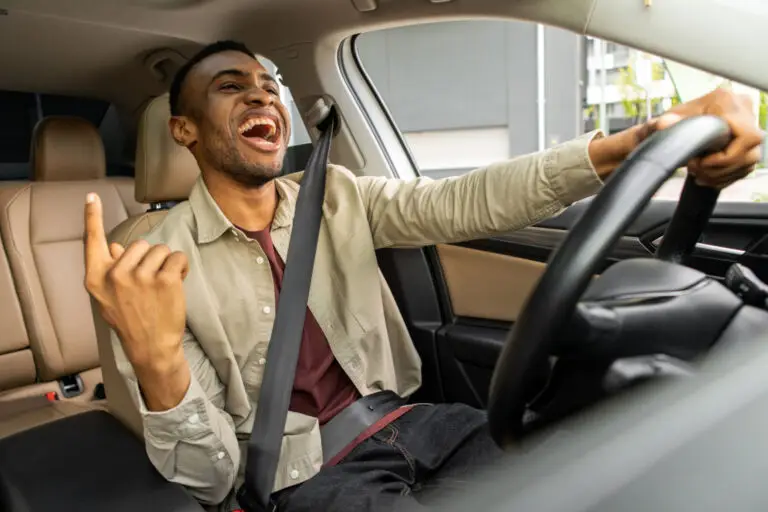 Man laughing and singing along while driving his car