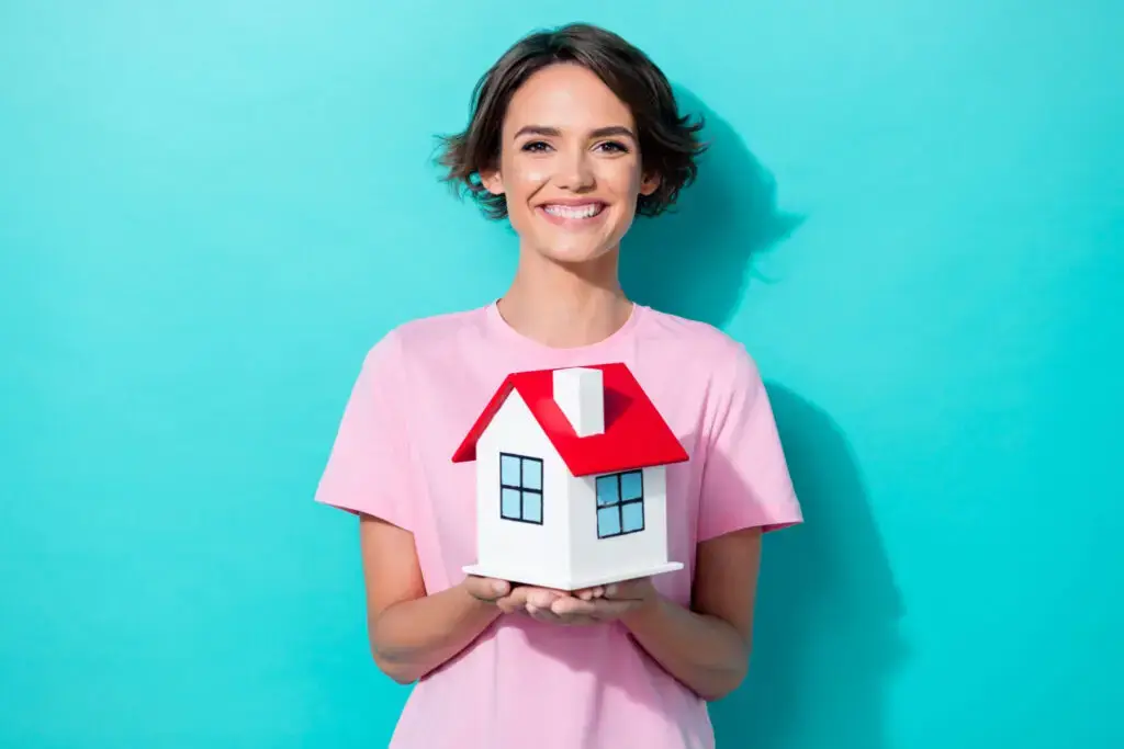 Smiling woman holding a small model house in both hands