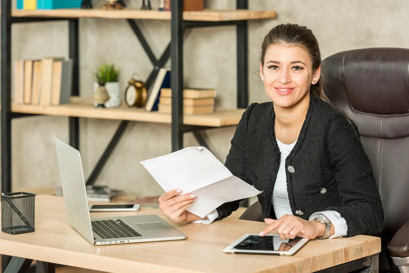 Independent loan officer smiling at her desk with client paperwork